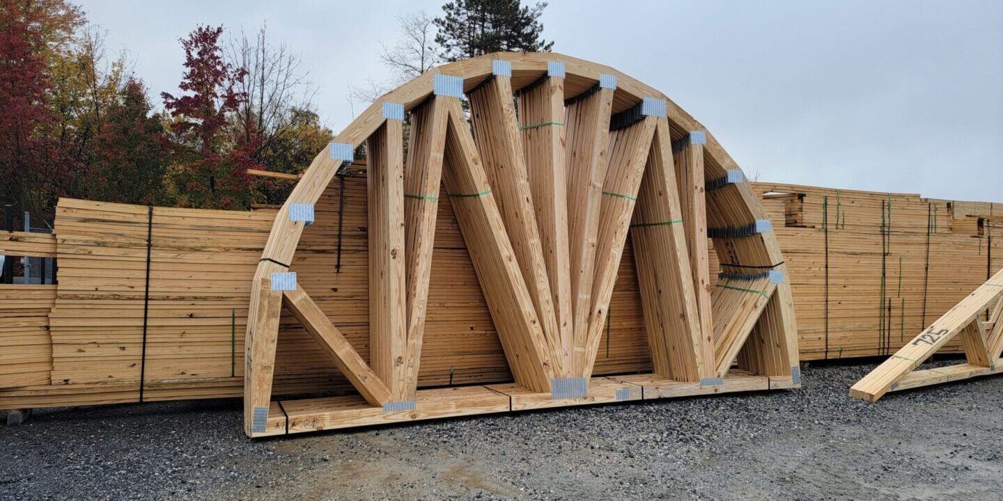 Large wooden arched trusses stacked outdoors